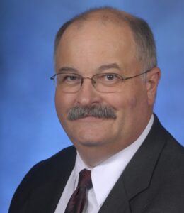 a man with a mustache wearing eye glasses and a business suit